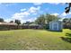 Wide shot of the grassy backyard with a hot tub, pergola, shed and wooden fence at 716 N Rockingham Ave, Tavares, FL 32778