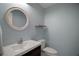 Stylish powder room with gray paint, modern sink, round mirror and a toilet at 716 N Rockingham Ave, Tavares, FL 32778