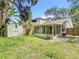Exterior view of the home featuring an enclosed porch and a storage shed in the overgrown backyard at 809 Sugar House Blvd, Port Orange, FL 32129