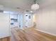 Open living room with wood floors, modern light fixture, and access to the kitchen and laundry area at 809 Sugar House Blvd, Port Orange, FL 32129