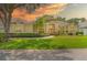 Picturesque one-story home with lush lawn, mature palm, and a beautifully lit sunset at 875 Bentley Green Cir, Winter Springs, FL 32708