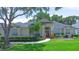 A well-manicured front lawn leads up to the tan home with a decorative glass front door and large windows at 875 Bentley Green Cir, Winter Springs, FL 32708