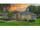 Inviting single-story home with lush landscaping, mature trees, and manicured lawn under a beautiful sunset sky at 875 Bentley Green Cir, Winter Springs, FL 32708