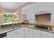 Well-appointed kitchen showcasing granite countertops, white cabinetry and a window overlooking the backyard at 875 Bentley Green Cir, Winter Springs, FL 32708