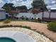 This backyard features a rock bed, mature trees, potted plants, and white vinyl fencing for privacy at 8850 Pine Bay Ct, Orlando, FL 32825