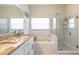 Bright bathroom featuring double sinks, granite countertops, a tub, and glass shower at 1021 Jaybee Ave, Davenport, FL 33897