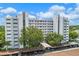 Exterior shot of white multi-story condo building with covered parking and mature trees at 1100 S Orlando Ave # 206, Maitland, FL 32751