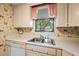 Close-up of a kitchen with white laminate countertops, tile floors, and a window with a view at 1100 S Orlando Ave # 206, Maitland, FL 32751