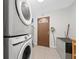 Convenient laundry room features a stacked washer and dryer, tile flooring and a utility sink at 1105 Arrowsmith Ave, Orlando, FL 32809