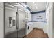 Well-lit laundry room features wooden floors, blue wallpaper, cabinets, and a stainless steel refrigerator at 1351 N Classic Ct, Longwood, FL 32779