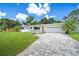 Charming home featuring a brick paver driveway, lush lawn, and four chairs sitting on a white stone garden at 2102 Ivanhoe Rd, Orlando, FL 32804
