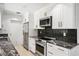Modern kitchen boasts stainless steel appliances, white cabinets, stylish black backsplash, and granite countertops at 2102 Ivanhoe Rd, Orlando, FL 32804