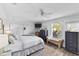 Cozy bedroom with a queen bed, wood floors, and stylish dresser, illuminated by natural light at 2356 Date Palm Dr, Edgewater, FL 32141