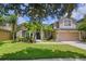 Charming two-story home featuring a lush green lawn and mature tropical landscaping at 2451 Ridgemoor Dr, Orlando, FL 32828