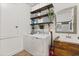 Functional laundry room with wooden shelves, washer, dryer, sink, and a rustic mirror at 31924 Geoff, Sorrento, FL 32776