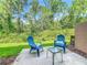 A cozy patio features a pair of blue Adirondack chairs and table with natural views at 3599 Caruso Pl, Oviedo, FL 32765