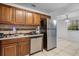 Bright kitchen with dark countertops, wooden cabinetry, stainless steel appliances, and tile floors at 3997 Versailles Dr # 3997F, Orlando, FL 32808