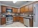 Well-lit kitchen with wooden cabinets, stainless steel appliances, tile backsplash, and tile flooring at 3997 Versailles Dr # 3997F, Orlando, FL 32808