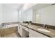 Bathroom featuring a soaking tub, quartz countertops, double sinks, white cabinets, tile flooring, and a large mirror at 4367 Rhyme St, Kissimmee, FL 34746
