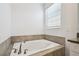 Close up of a relaxing soaking tub with quartz countertops, tile flooring, and a window with blinds at 4367 Rhyme St, Kissimmee, FL 34746