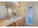 Bathroom vanity featuring double sinks, decorative lighting, and a unique stained glass door at 5226 Smokey Water Ln, Oviedo, FL 32765