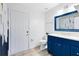Bathroom with a blue vanity, sink, toilet, tile flooring, white door, and striking blue-and-gold accent wall at 538 Murray St, Osteen, FL 32764