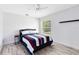 Bedroom with fan, window, grey wood flooring, and a queen bed with stylish blue, white, and red bedding at 538 Murray St, Osteen, FL 32764