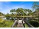 Scenic view of a pond with a wooden dock, surrounded by vibrant green grass and tall trees, offering a tranquil retreat at 538 Murray St, Osteen, FL 32764