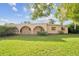 Inviting single-story home featuring a unique arched porch and lush front lawn under a bright sky at 5527 Sandalwood Dr, Orlando, FL 32839