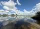 Scenic view of the lake featuring clear water, reflections, and a blue sky with fluffy clouds at 5527 Sandalwood Dr, Orlando, FL 32839