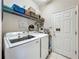 Functional laundry room with modern washer and dryer, storage shelves, and tile flooring at 5852 Stafford Springs Trl, Orlando, FL 32829