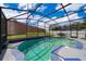 This screened in in-ground pool features string lights and a patio area for entertaining at 603 Cypress Tree Ct, Orlando, FL 32825