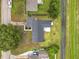 Aerial view of the L-shaped home with a dark gray roof, green yard and a small patio in the backyard at 609 Brockway Ave, Orlando, FL 32807