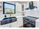 The bright kitchen features a black sink, modern appliances and a black hood with decorative backsplash tiles at 609 Brockway Ave, Orlando, FL 32807