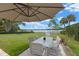 Outdoor patio with dining set and shade umbrella overlooking manicured lawn and lake at 641 Virginia Dr, Winter Park, FL 32789
