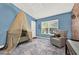 The charming bedroom has a crib with canopy, exposed brick accent wall, gray chair, and blue rug at 6931 Sperone St, Orlando, FL 32819