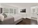 This main bedroom features a neutral palette, ensuite bath, dark wood floors and a picture-frame television at 6931 Sperone St, Orlando, FL 32819