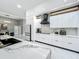 This modern kitchen features sleek white cabinets, a black range hood, and a marble backsplash for a clean and stylish look at 704 Forest View Ct, Winter Springs, FL 32708