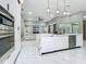 A modern kitchen with white cabinets, marble countertops, stainless steel appliances, and an adjacent living area at 704 Forest View Ct, Winter Springs, FL 32708