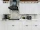 A modern kitchen featuring a black range hood, marble backsplash, white cabinets, and stainless steel appliances at 704 Forest View Ct, Winter Springs, FL 32708