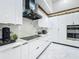 A contemporary kitchen with a black range hood, marble backsplash, white cabinets, and stainless steel appliances at 704 Forest View Ct, Winter Springs, FL 32708
