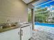 Covered outdoor kitchen boasts a stainless steel sink and refrigerator for easy poolside entertaining at 704 Forest View Ct, Winter Springs, FL 32708