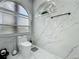 Contemporary bathroom showcasing a sleek toilet, arched window, and marble-patterned tile at 704 Forest View Ct, Winter Springs, FL 32708