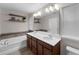 Bathroom featuring double sinks, wood cabinets, and a soaking tub with decorative tile surround at 8968 Hildreth Ave, Orlando, FL 32832