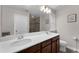 Bright bathroom featuring double sinks, dark wood cabinetry, and a glass-enclosed shower at 8968 Hildreth Ave, Orlando, FL 32832