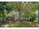 Backyard view of white shed in landscaped garden with mature trees at 9031 Stonebury Way, Orlando, FL 32832