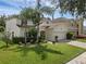 Attractive two-story home with a lush lawn, palm trees, and a brick paved driveway at 9031 Stonebury Way, Orlando, FL 32832