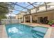 Backyard view of screened-in pool and spa area with tile and brick at 9031 Stonebury Way, Orlando, FL 32832