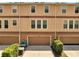 Townhome featuring tan siding, brown trim, garage doors and landscaping at 9997 Town Lake Dr, Orlando, FL 32832