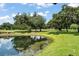 Picturesque pond view on the golf course surrounded by lush greenery, reflecting the clear blue sky above at 10254 Hart Branch Cir, Orlando, FL 32832
